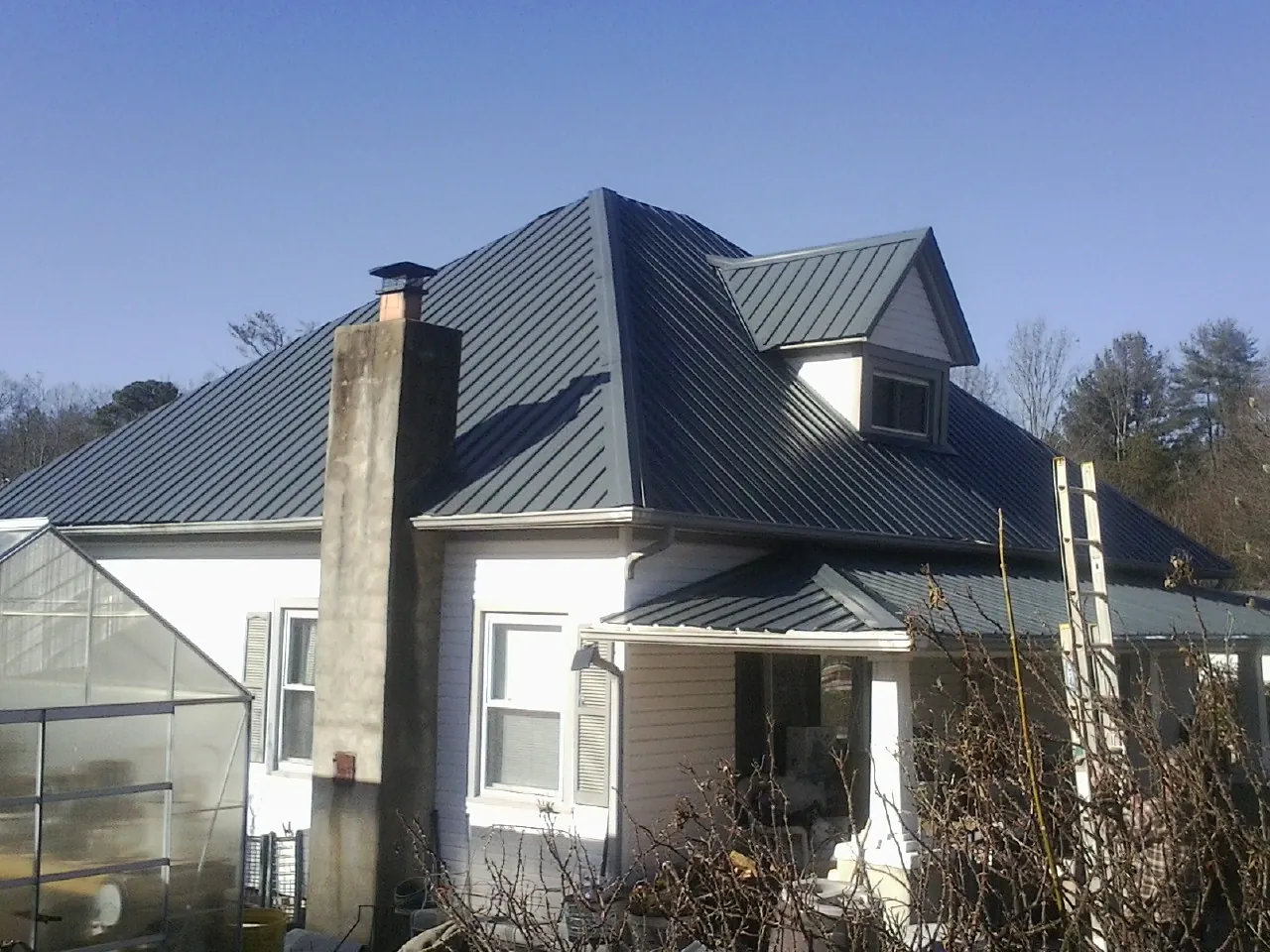 Dark blue standing seam metal roof on a white farmhouse with dormer — Slate & Tile Roof Repair by Roofing Brothers in Dunfermline