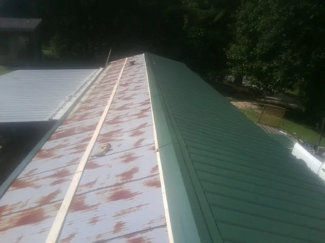 Old rusted panels beside newly installed green metal roofing — Wind Damage Roof Repair by Roofing Brothers in Dunfermline