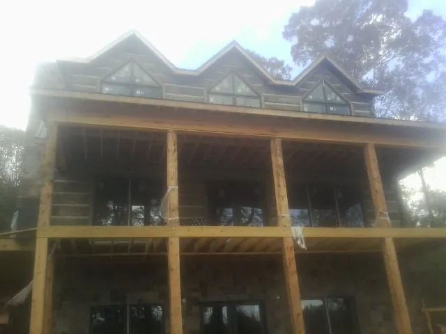 Dormers and porch framing on a large log home under construction — Roof Coating work by our crew in Dunfermline