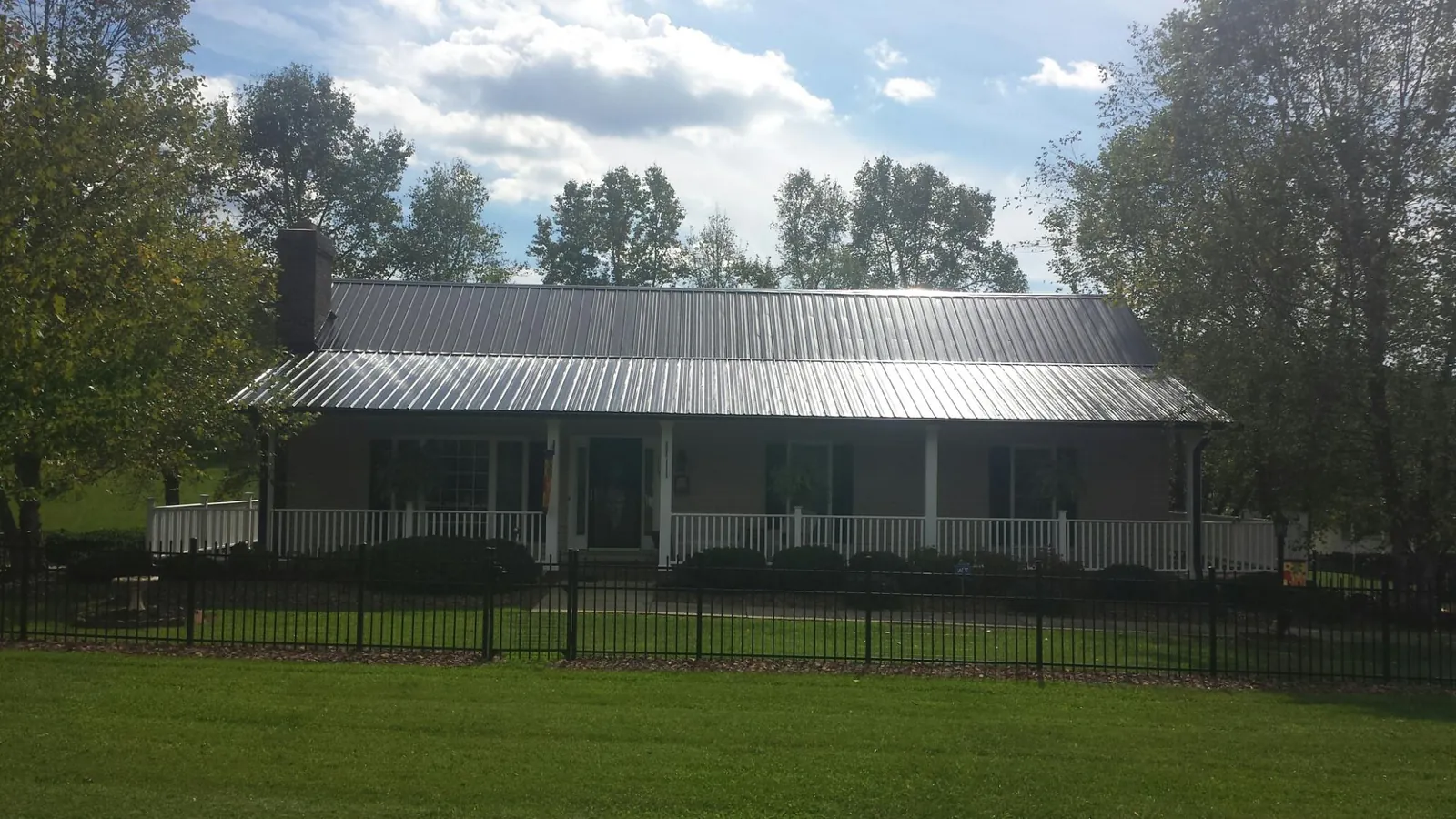 Gray metal roof on a brick ranch with a full width front porch — Gutter Guard Installation work by our crew in Dunfermline