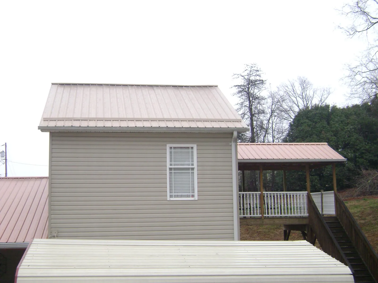Tan metal roofs on a two story addition and attached porch, from a Roof Replacement job in Dunfermline
