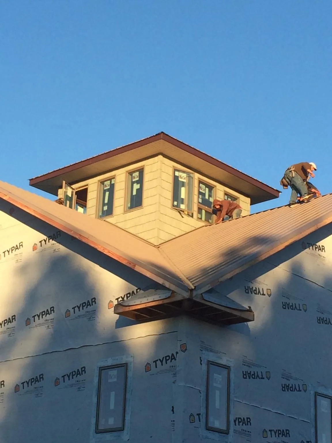 Roofers working around a rooftop cupola on a new metal roof at sunset — Roof Waterproofing in Dunfermline by Roofing Brothers